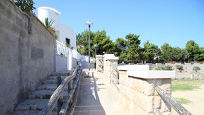 A stone staircase with a wooden handrail leading to a white building with a dome.