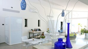 A modern kitchen with white cabinetry, a dining area with a white table and chairs, and a large window providing natural light.