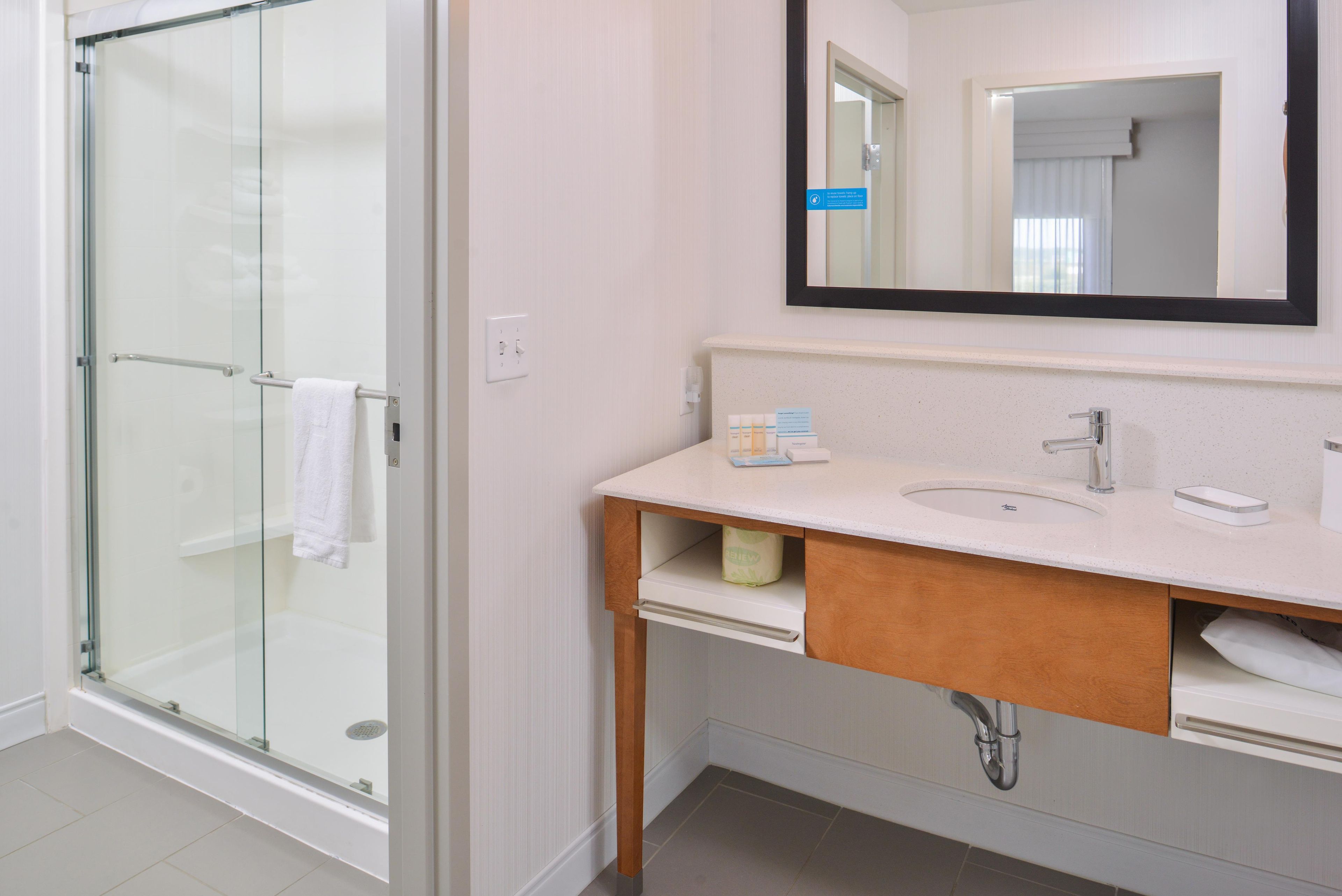 A modern bathroom with a glass shower enclosure, a white sink, and a mirror above the vanity.