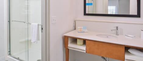 A modern bathroom with a glass shower enclosure, a white sink, and a mirror above the vanity.