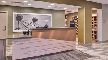 A reception desk with a large poster, a sign for Hilton Hotels, and a treats shop.