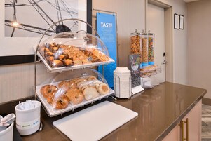 A breakfast buffet with various pastries and bread, a sign for Taste Pool Mix, and a cereal dispenser.