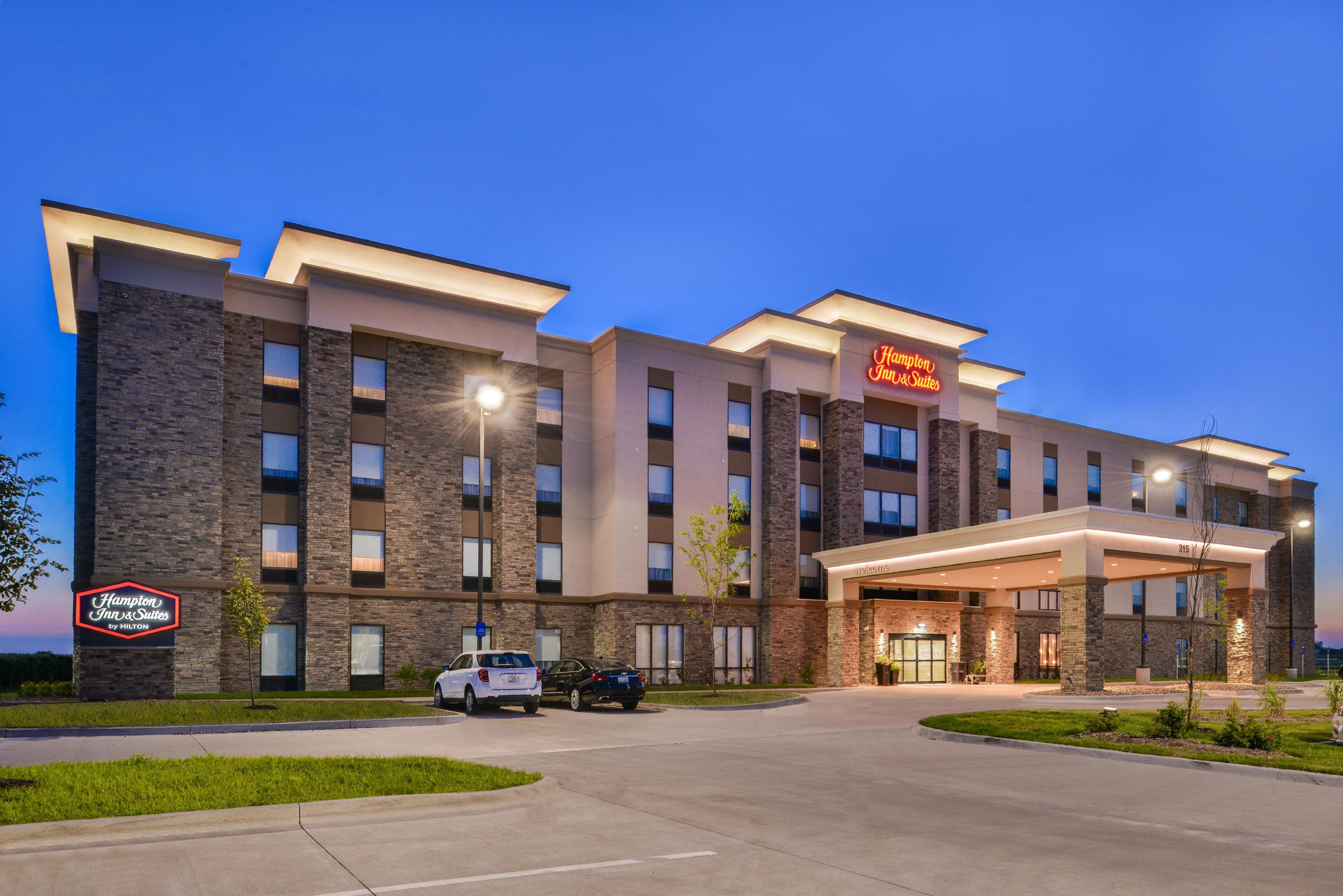 Un hôtel Hampton Inn & Suites au design moderne, avec une façade en briques et une entrée accueillante.
