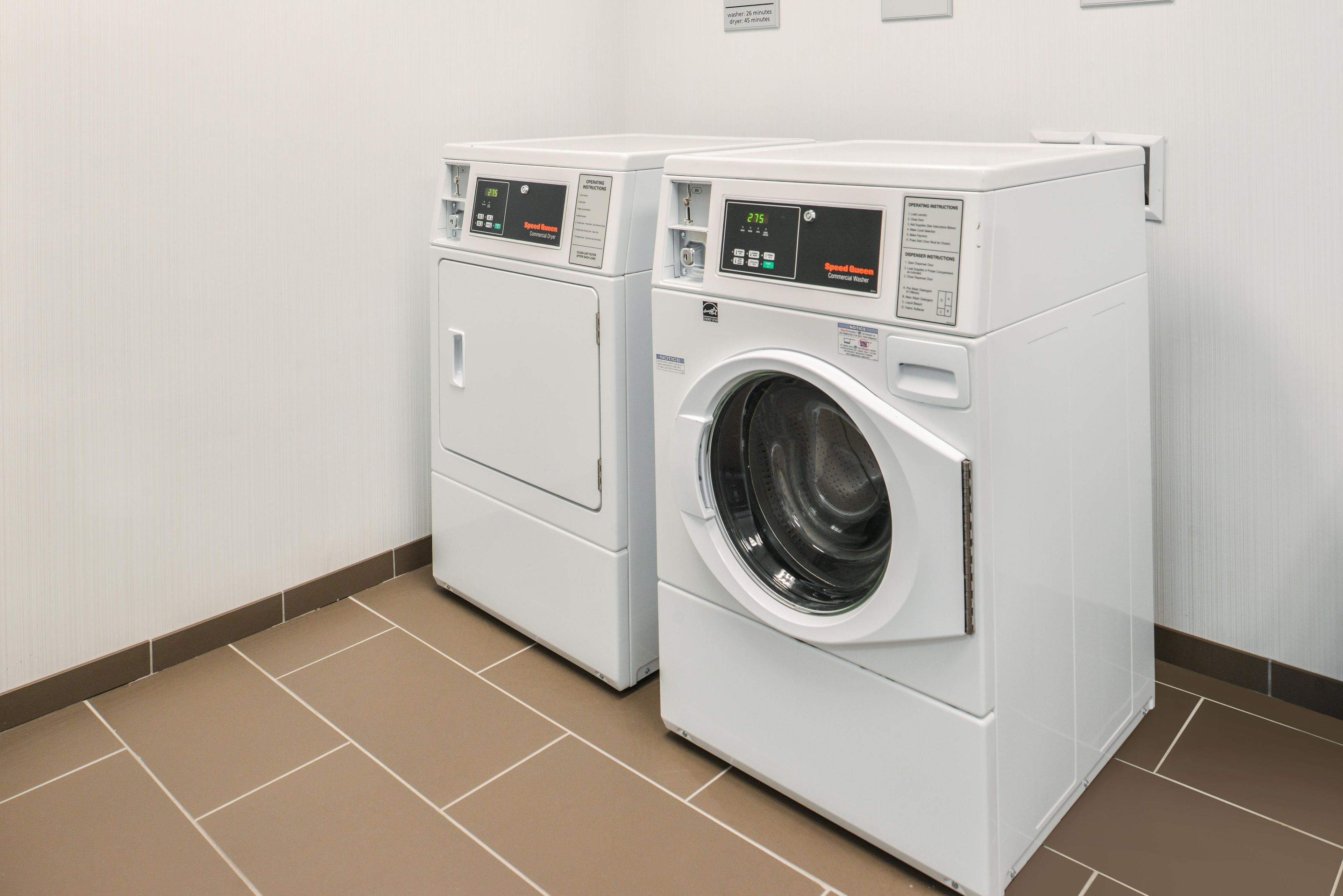 Two front-loading washing machines in a laundry room with a tiled floor.