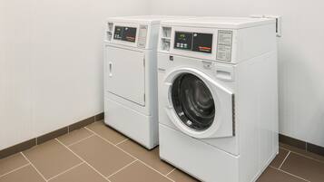 Two front-loading washing machines in a laundry room with a tiled floor.