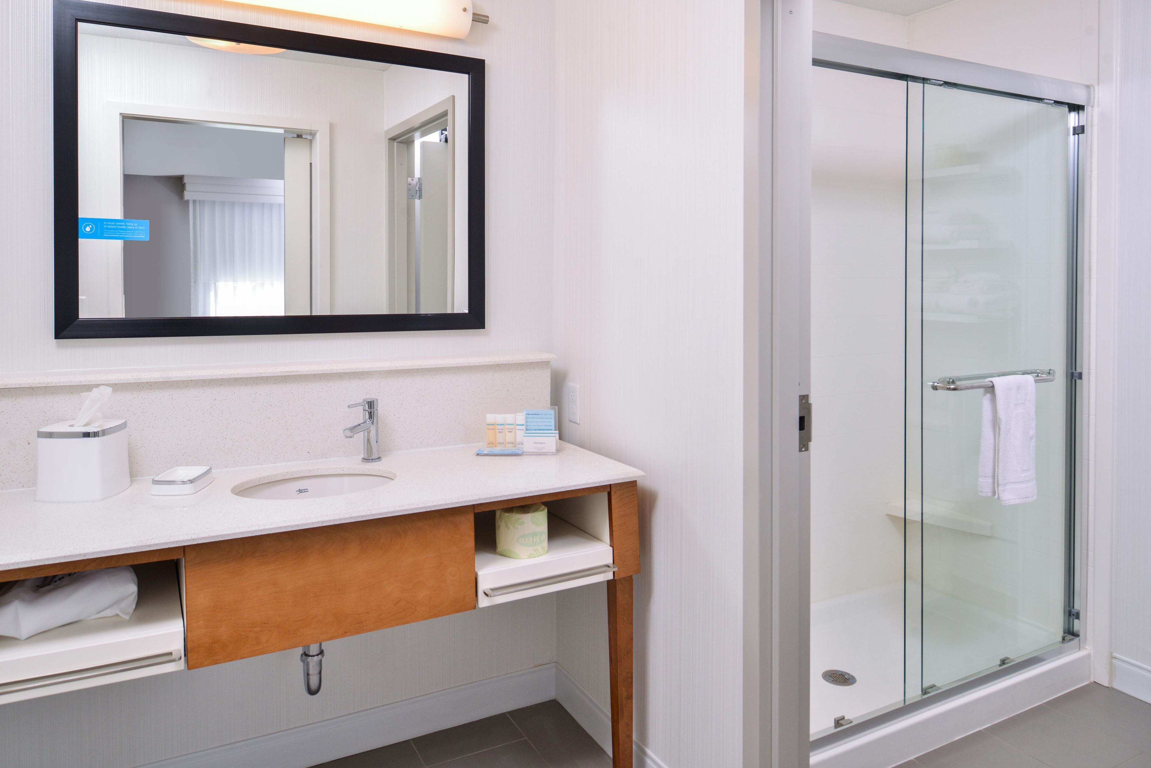 A modern bathroom with a sink, mirror, and glass shower enclosure.
