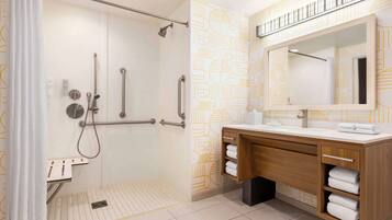A modern bathroom with a walk-in shower, grab bars, a large mirror, and a vanity with towels.