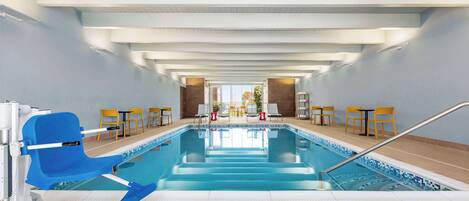 Une piscine intérieure avec une chaise bleue, des chaises jaunes et un toit ouvrant.