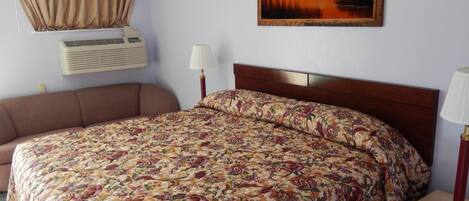 Habitación de hotel con una cama grande, un sofá, un cuadro en la pared y un equipo de aire acondicionado.