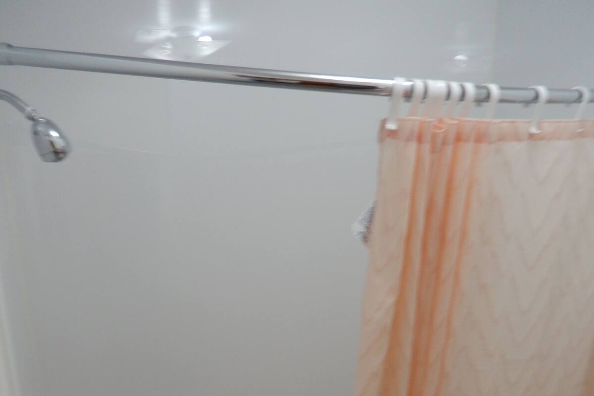 A bathroom with a shower curtain, a bathtub, and a toilet.