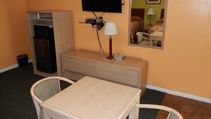 A hotel room with a desk, chair, television, and a mirror. - Townsman Motel (Boise City)