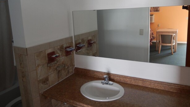 A bathroom with a white sink, a mirror, and a towel rack. - Townsman Motel (Boise City)
