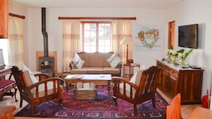 A living room with a sofa, chairs, a coffee table, a fireplace, and a television. - Aan De Bergen Guesthouse South Africa (Swellendam)