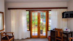 A room with a wooden desk, two chairs, a television, and a large window with curtains. - Aan De Bergen Guesthouse South Africa (Swellendam)