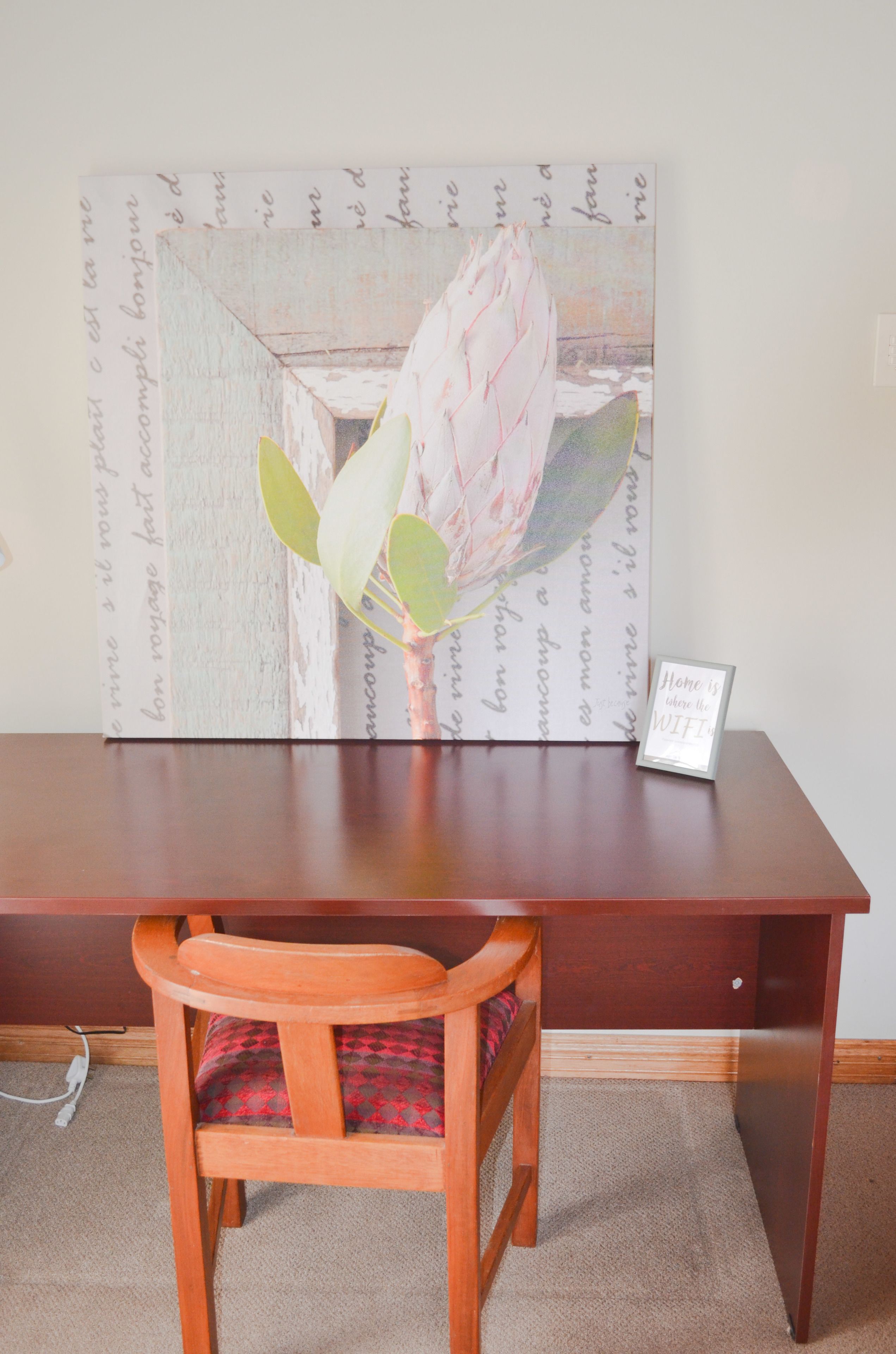 A wooden desk with a framed picture of a flower and a sign that says "Home is where the WIFI is."