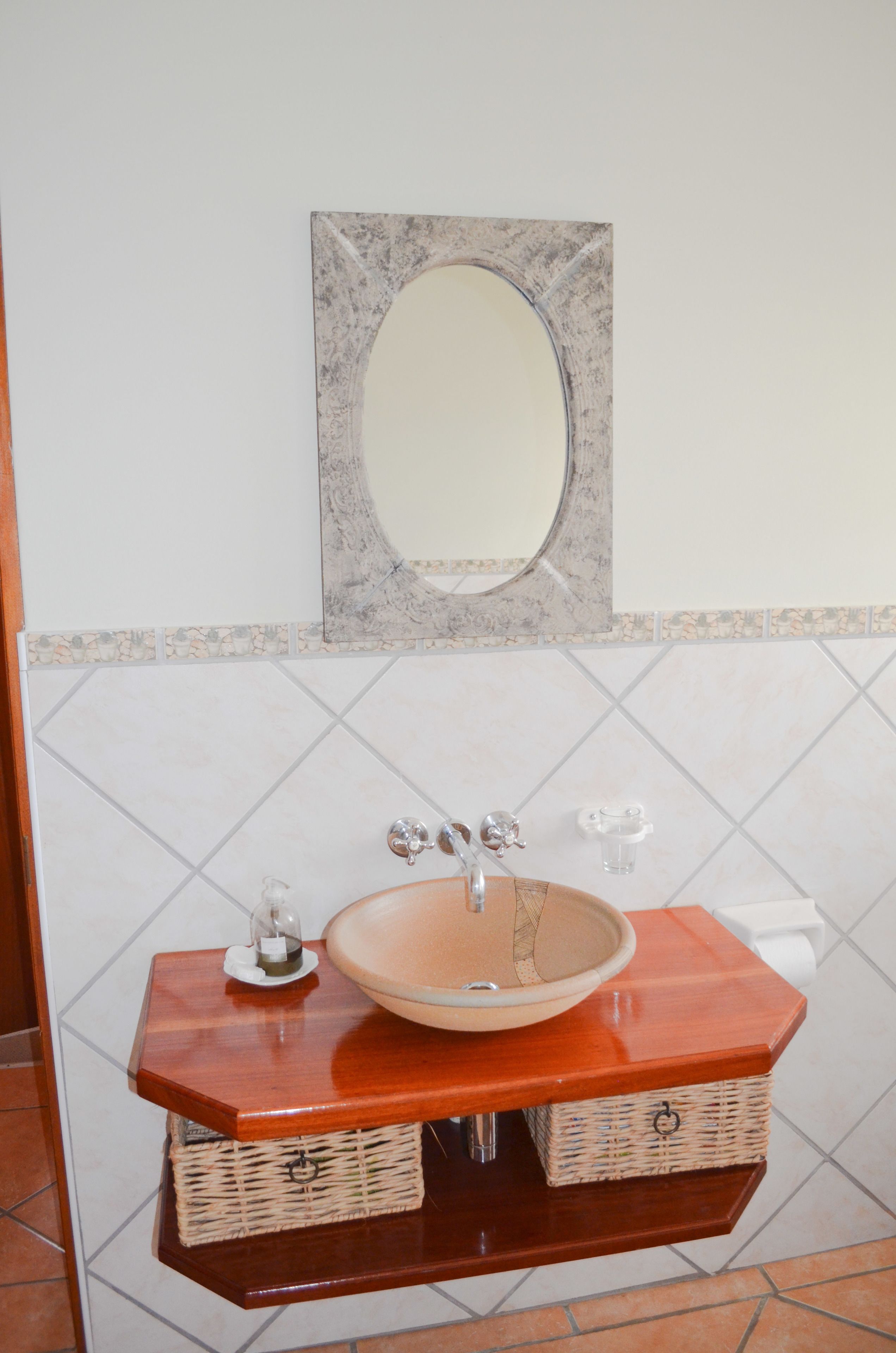 A bathroom with a wooden vanity, a round sink, and a mirror above it.