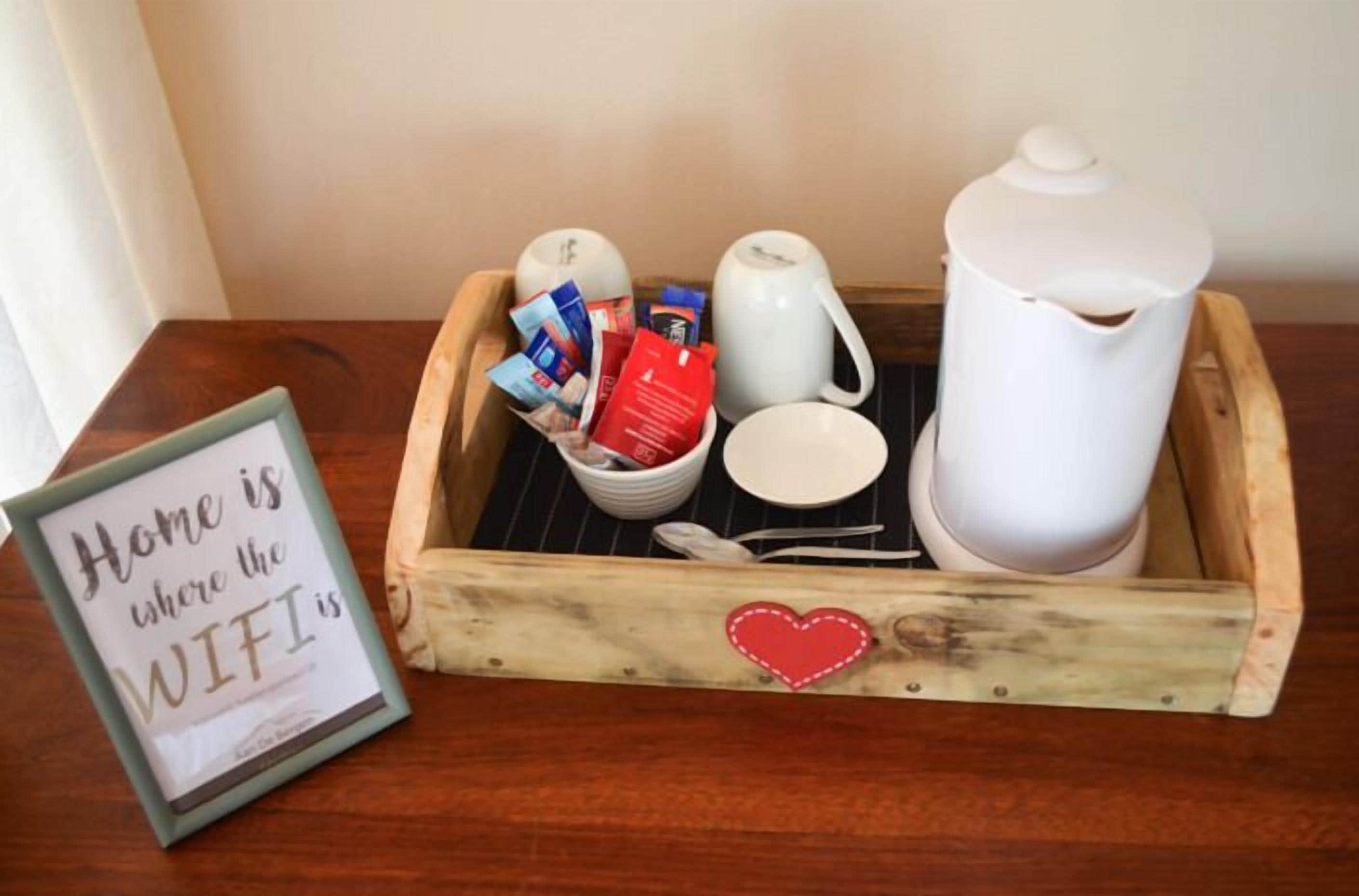 A wooden tray with a coffee maker, mug, spoon, and a framed sign stating "Home is where the WIFI is."