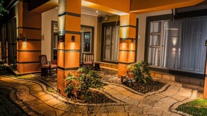 A well-lit outdoor area with stone pathways, potted plants, and seating arrangements. - Home Guesthouse (Rustenburg)