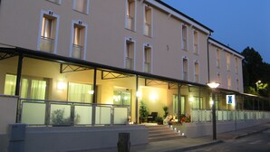 A hotel with a covered entrance, multiple windows, and a sign indicating a public restroom. - Hotel Fontanelle (Bertinoro)
