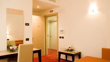 Habitación de hotel con cama, escritorio y silla. Se ve una puerta que conduce a otra habitación.