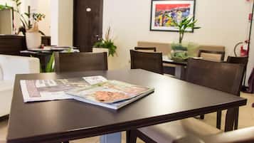 A dining area with a table set for two, featuring a magazine on the table.