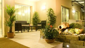A well-lit indoor space with a seating area, potted plants, and a stone wall. - Hotel Fontanelle (Bertinoro)