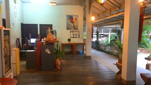 A spacious lobby with a wooden floor, a reception desk, and a large window overlooking a garden. - The Heart of Pai Resort (Pai)