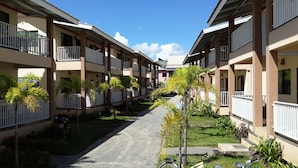 A row of multi-story buildings with balconies, a central pathway, and small trees. - The Heart of Pai Resort (Pai)