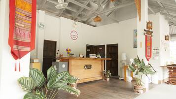 Ein Empfangsschalter mit einer Holztresen, einer Uhr und einem Schild mit der Aufschrift 'The Heart of Pai Resort'.