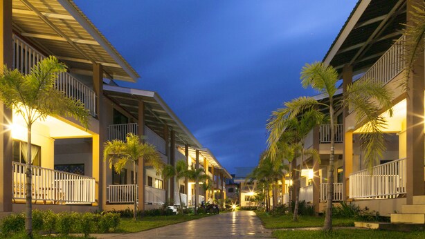 A hotel corridor with multiple balconies, palm trees, and a nighttime sky. - The Heart of Pai Resort (Pai)