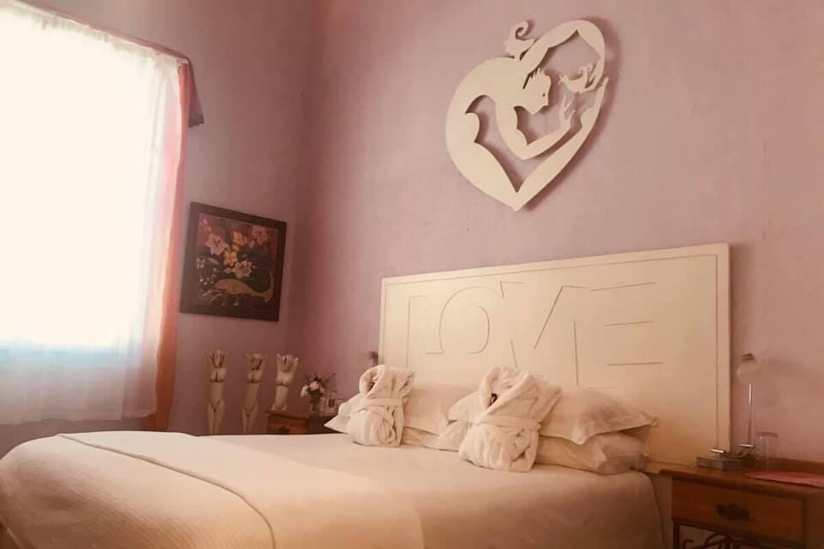 Ein Schlafzimmer mit einem Bett, einer herzförmigen Wanddekoration und einem gerahmten Bild.