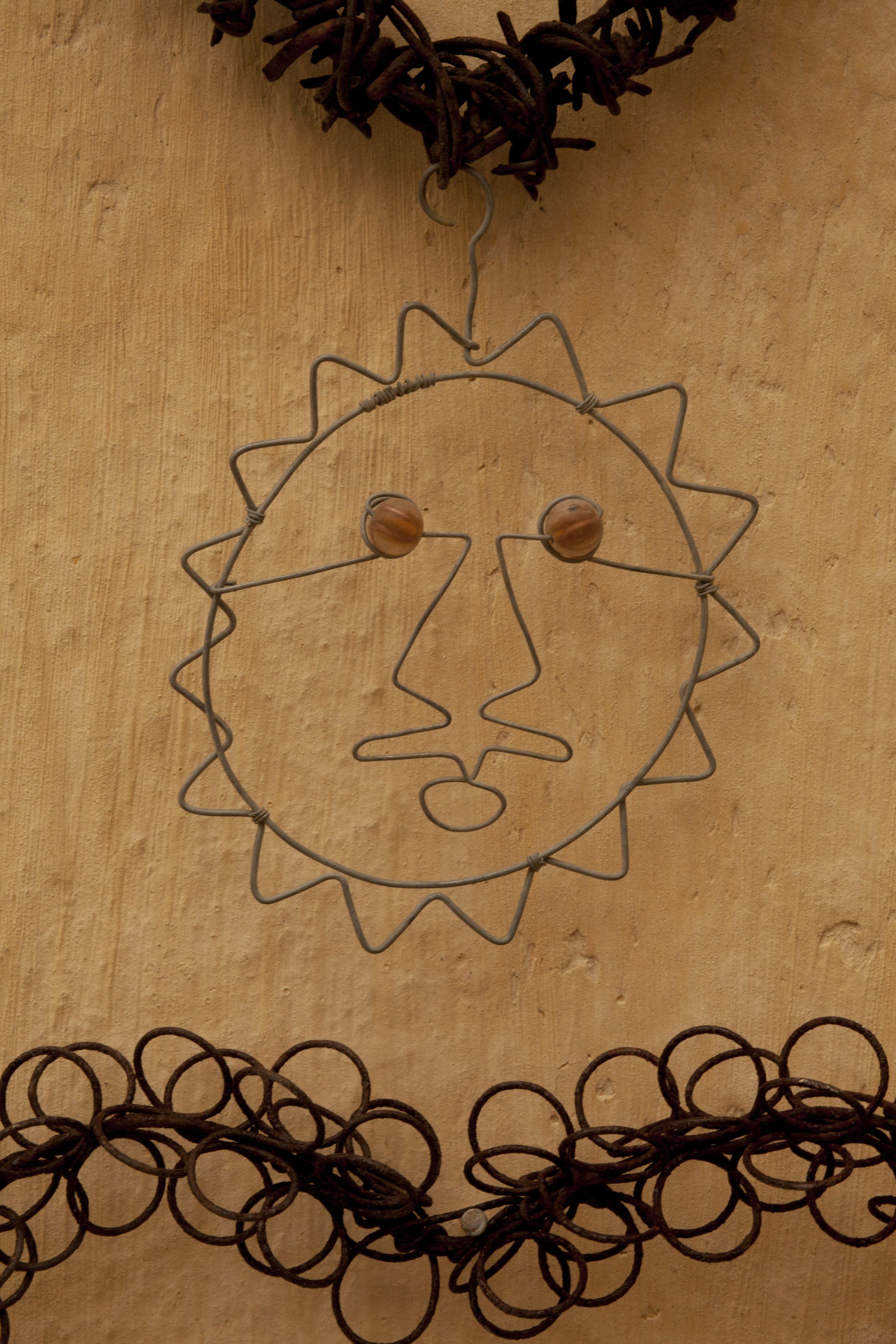 Pared de madera con un dibujo que simula un sol y una guirnalda de adornos circulares.