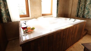 Una bañera con revestimiento de madera, una copa de vino tinto y un plato de fruta.