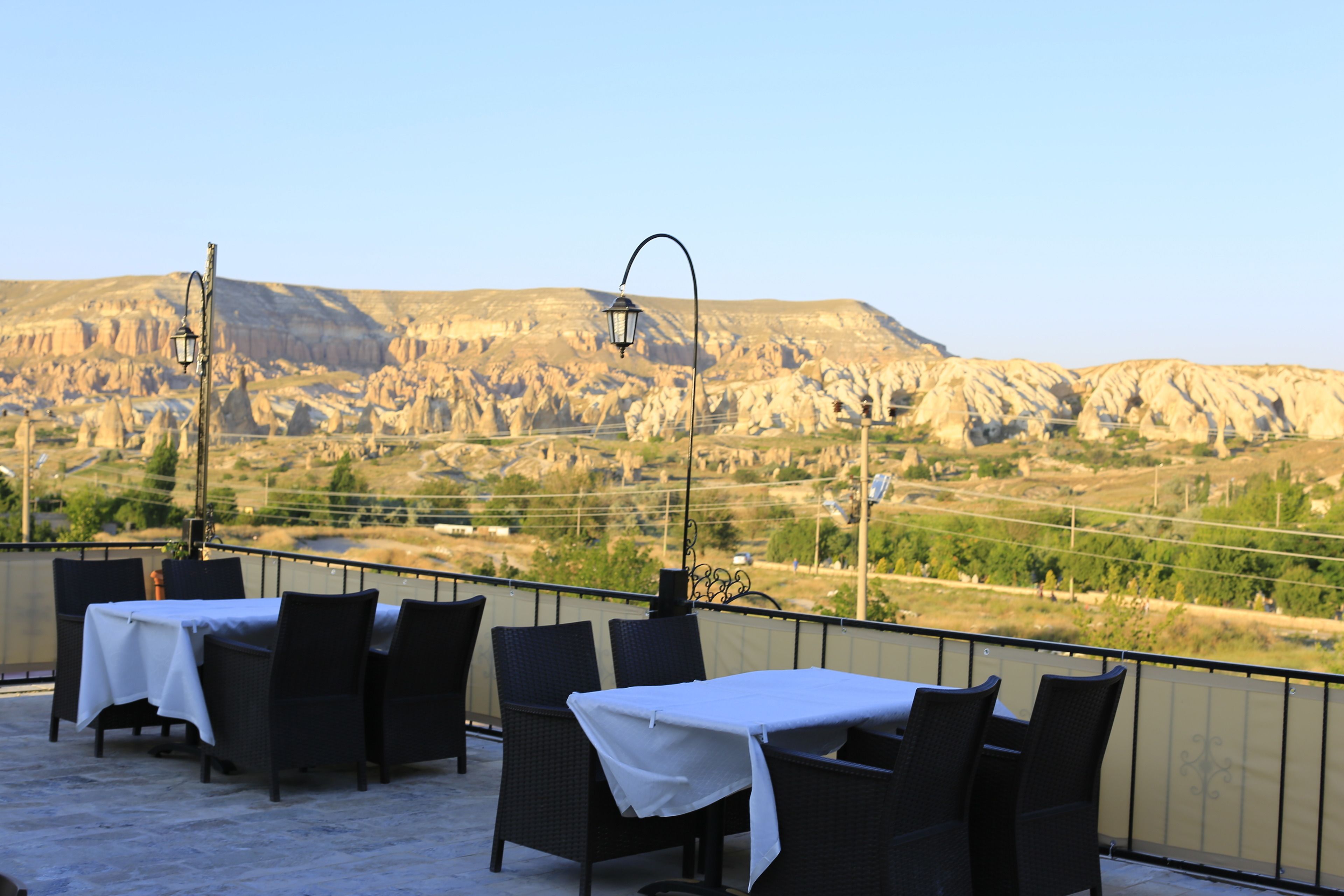 A terrace with tables and chairs, a lamp, and a view of a mountainous landscape.