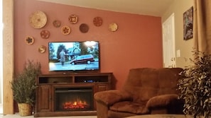 A living room with a fireplace, a television, and a brown armchair.