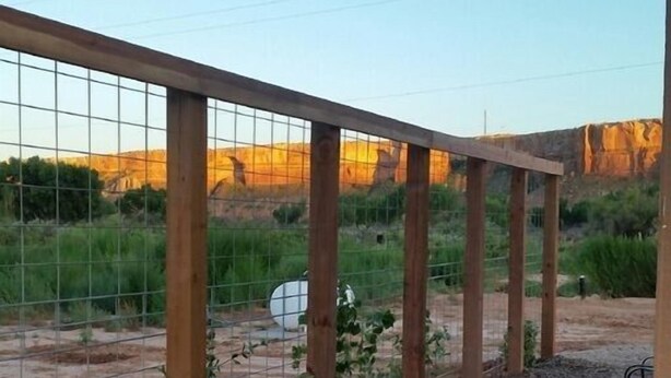 Un pati amb una pèrgola de fusta, terra de grava i vistes a un paisatge natural.