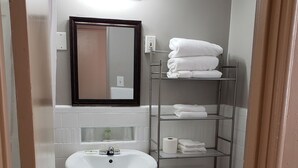 Un baño con lavamanos pedestal, inodoro, toallero y espejo con iluminación.