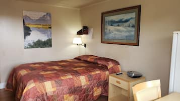 Une chambre à coucher avec un lit, un bureau, une chaise, une lampe et deux tableaux encadrés accrochés au mur.