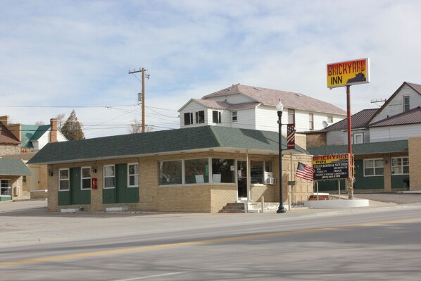 A small brick building with a green roof, a sign for Brickyard Inn, and an American flag.