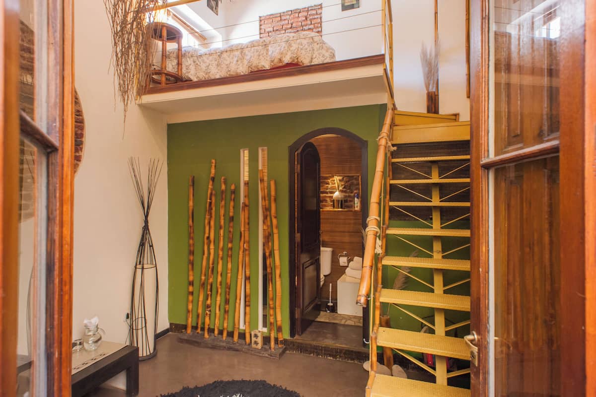 A hallway with a green wall, a wooden staircase, and bamboo decorations.