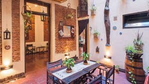 Un comedor acogedor con decoración rústica, que incluye paredes de ladrillo visto, plantas colgantes y muebles de madera.