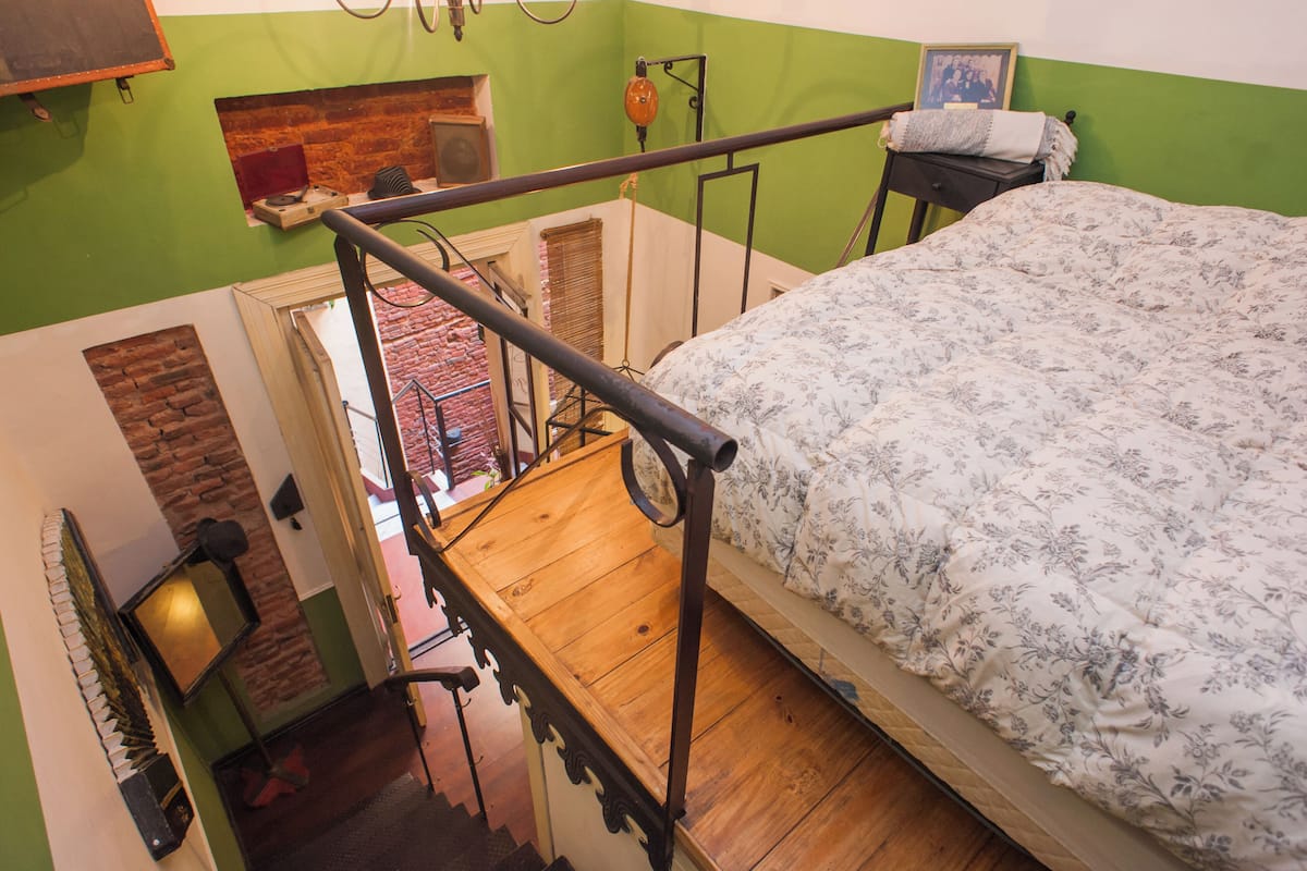 A bedroom with a wooden bed, green walls, and a brick wall.
