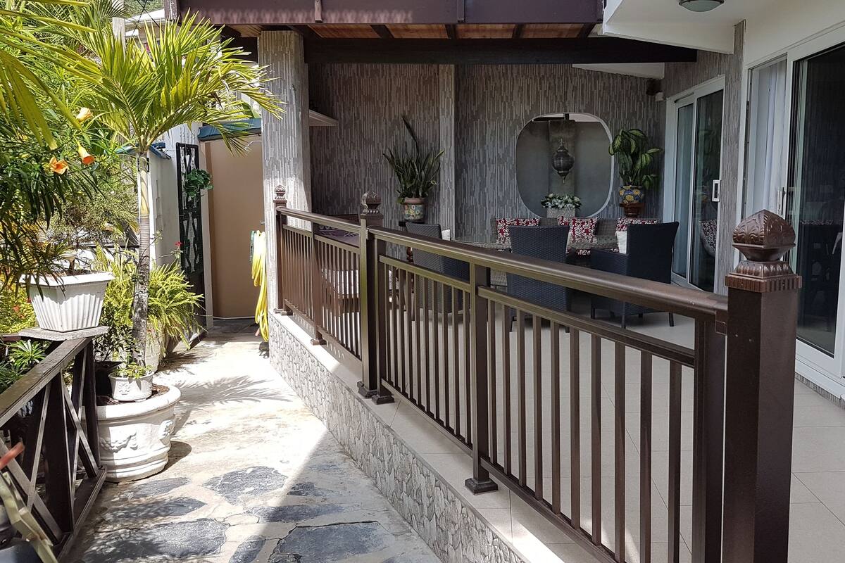 A balcony with a stone floor, potted plants, and a railing.