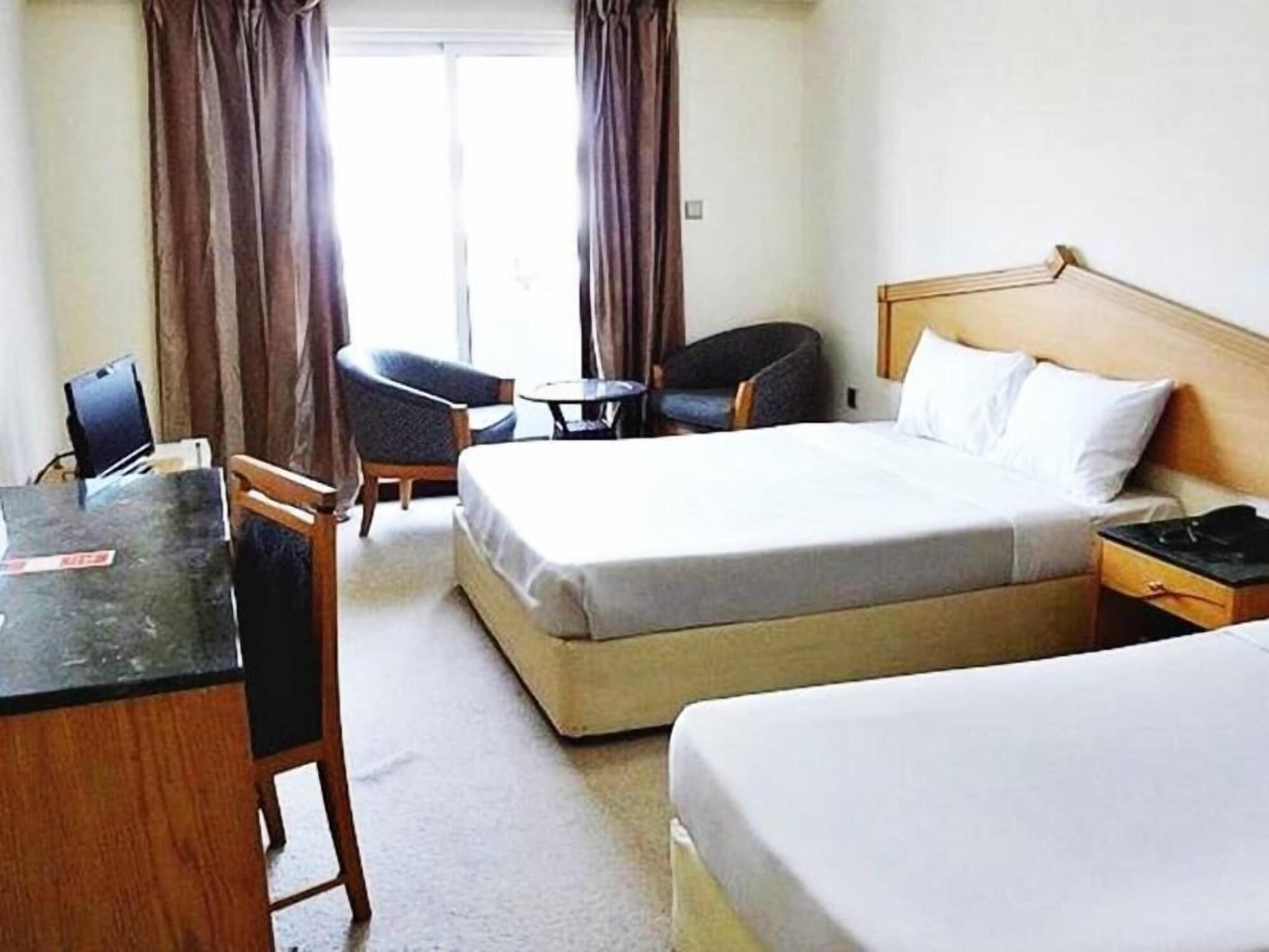 A hotel room with a bed, a desk, a chair, and a small table.