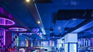 Eine moderne Bar mit Neonbeleuchtung, Sitzgelegenheiten und einem DJ-Pult.