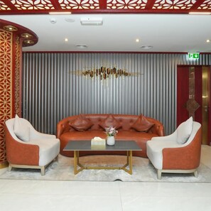 A lobby with a sofa and armchairs, a coffee table, and a decorative wall with vertical lines. - Rush Inn Hotel (Dubai)