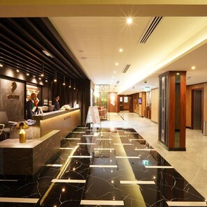 A hotel reception area with a marble floor, a reception desk, and a waiting area with seating. - Rush Inn Hotel (Dubai)