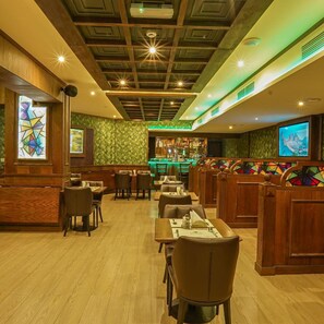 A restaurant with wooden furniture, a bar area, and a large screen. - Rush Inn Hotel (Dubai)