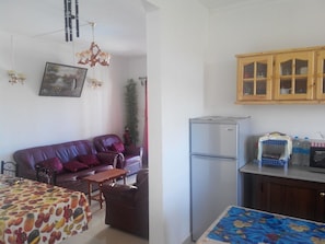Un espacio habitable compacto con sofá, mesa de comedor, refrigerador y cocina con armarios de madera.
