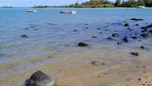 Une plage avec une eau claire, des rochers et des bateaux.